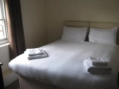 a bedroom with a bed with two towels on it at Rose and Crown Hotel in Haverhill