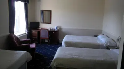 a hotel room with two beds and a chair and a mirror at Rose and Crown Hotel in Haverhill