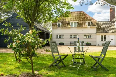 a table and chairs in the yard of a house at Marsh Lodge in Aldeburgh