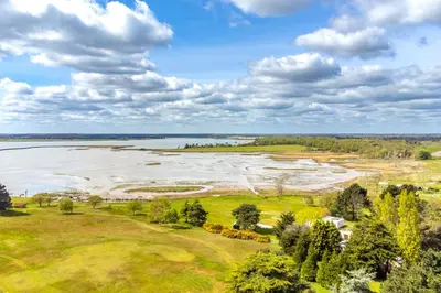 an aerial view of a field with water and trees at River View in Aldeburgh