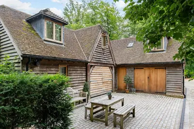a house with a picnic table and a wooden garage at Hertford Barn conversion in Hertford