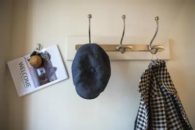 a hat and two shirts hanging on a wall at Hertford Barn conversion in Hertford