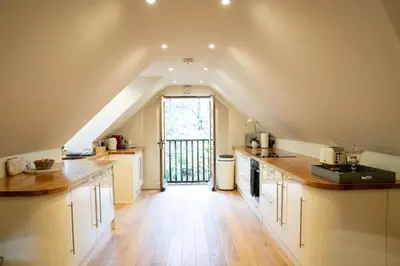 a kitchen with white cabinets and a large window at Hertford Barn conversion in Hertford