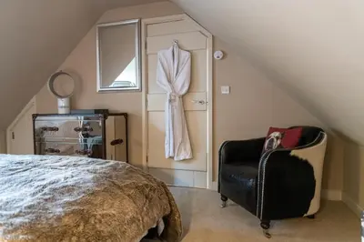 a attic bedroom with a bed and a chair at Hertford Barn conversion in Hertford