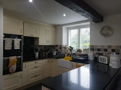 a kitchen with white cabinets and a black counter top at Olde Farm Holiday Cottages in Banham