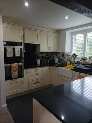a kitchen with white cabinets and a black counter top at Olde Farm Holiday Cottages in Banham