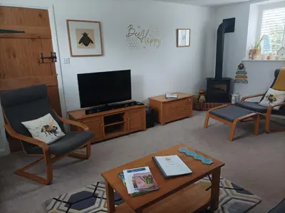 a living room with a tv and chairs and a table at Olde Farm Holiday Cottages in Banham