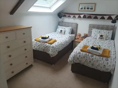 a small bedroom with two beds and a dresser at Olde Farm Holiday Cottages in Banham