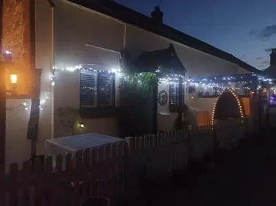 a house with christmas lights on the side of it at Olde Farm Holiday Cottages in Banham