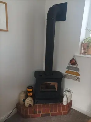 a black stove in a corner of a room at Olde Farm Holiday Cottages in Banham