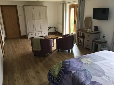 a bedroom with a bed and chairs and a desk at Grove Barn Bed and Breakfast in Harleston