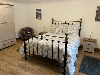 a bedroom with a black bed and a wooden floor at Grove Barn Bed and Breakfast in Harleston
