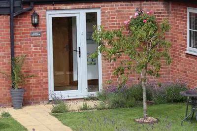 a red brick house with a white door and a tree at Grove Barn Bed and Breakfast in Harleston