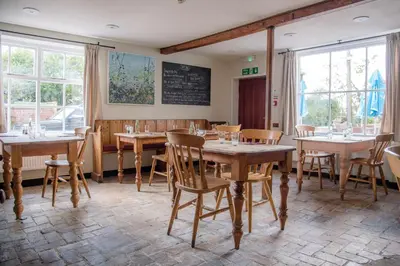a restaurant with wooden tables and chairs and windows at The Golden Key in Snape