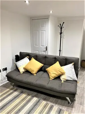 a gray couch with yellow pillows in a living room at Star Apartment Ipswich, A Hidden Gem near the Waterfront in Ipswich