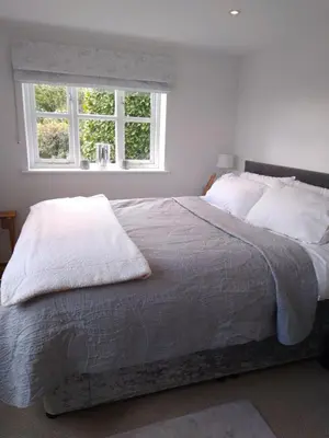 a bedroom with a large bed with two windows at Brick Kiln Apartment in Campsea Ashe