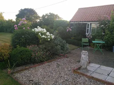 a garden with a table and some flowers and a house at Brick Kiln Apartment in Campsea Ashe