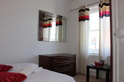 a bedroom with a bed and a dresser and a mirror at The George Hotel Stansted Airport in Bishops Stortford