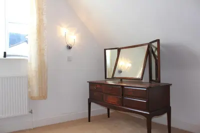 a dresser with a mirror on it next to a window at The George Hotel Stansted Airport in Bishops Stortford