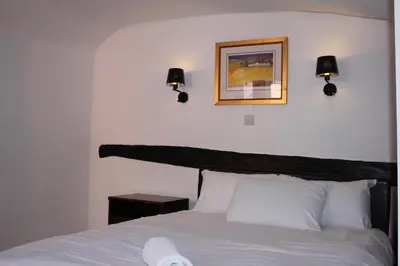 a bedroom with a white bed with two lights on the wall at The George Hotel Stansted Airport in Bishops Stortford