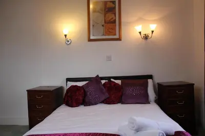 a bedroom with a bed with two night stands and two lights at The George Hotel Stansted Airport in Bishops Stortford