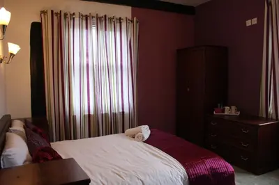 a bedroom with a bed and a dresser and a window at The George Hotel Stansted Airport in Bishops Stortford