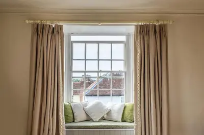 a window seat with pillows in front of a window at The Black Lion, Long Melford in Long Melford