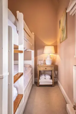 a bedroom with bunk beds and a table with a lamp at The Black Lion, Long Melford in Long Melford