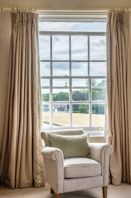 a living room with a chair and a large window at The Black Lion, Long Melford in Long Melford