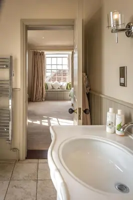 a bathroom with a white sink and a living room at The Black Lion, Long Melford in Long Melford