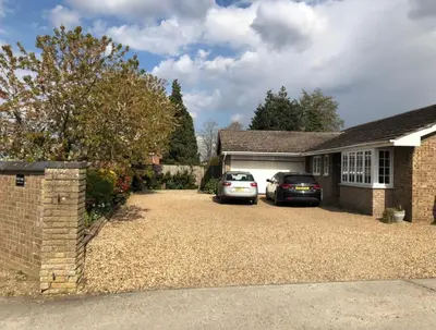 a house with two cars parked in a driveway at The Annexe at Asbit Lodge in Mildenhall