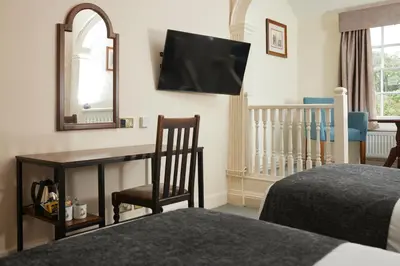 a bedroom with a bed and a desk and a mirror at Bull Hotel by Greene King Inns in Long Melford