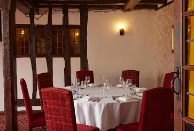 a dining room with a table and red chairs at Bull Hotel by Greene King Inns in Long Melford