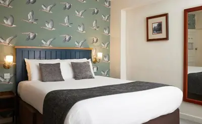 a bedroom with a bed with birds on the wall at Bull Hotel by Greene King Inns in Long Melford