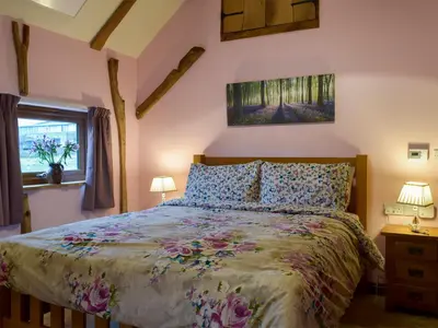 a bedroom with a bed and two lamps and a window at Chick Hatch Barn in Kelsale