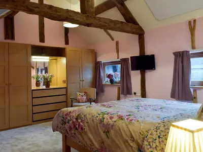a bedroom with a bed and a dresser and a television at Chick Hatch Barn in Kelsale