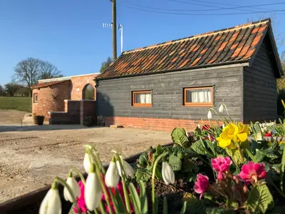 a house with a bunch of flowers in front of it at Chick Hatch Barn in Kelsale
