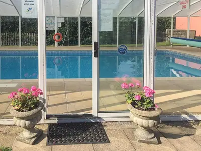 a swimming pool and two pots with pink flowers in them at Old Dairy - Ukc3169 in Walpole