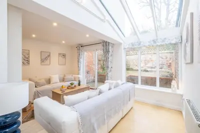 a living room with white furniture and a large window at 67 Pebble Cottage in Aldeburgh