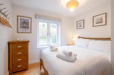 a bedroom with a white bed and a window at 67 Pebble Cottage in Aldeburgh