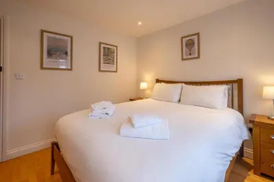 a bedroom with a large white bed with towels on it at 67 Pebble Cottage in Aldeburgh