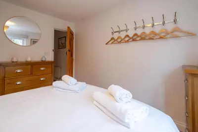 a bedroom with a white bed with towels on it at 67 Pebble Cottage in Aldeburgh