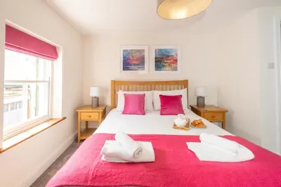 a bedroom with a large white bed with pink pillows at Avocet Cottage in Aldeburgh