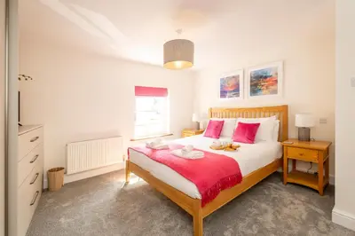 a bedroom with a large bed with pink pillows at Avocet Cottage in Aldeburgh
