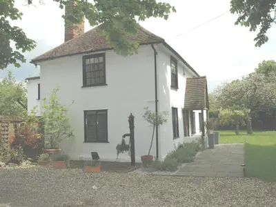 a white house with a cow statue in front of it at The White House in Bishops Stortford