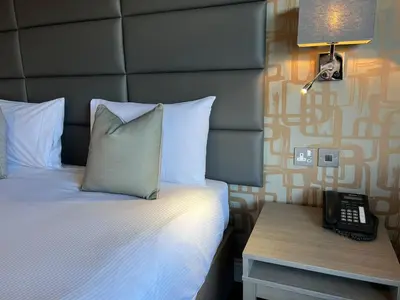 a hotel room with a bed and a phone on a table at The Essex Golf & Country Club Hotel in Coggeshall