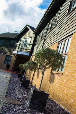 a house with two trees in front of a building at The Essex Golf & Country Club Hotel in Coggeshall