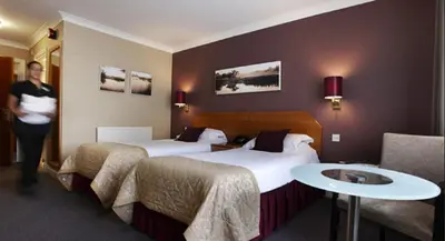 a hotel room with two beds and a woman in a room at The Essex Golf & Country Club Hotel in Coggeshall