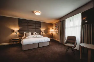 a hotel room with a bed and a chair at The Essex Golf & Country Club Hotel in Coggeshall