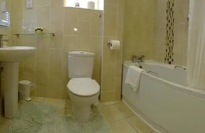 a bathroom with a toilet and a tub and a sink at The Chudleigh in Clacton-on-Sea